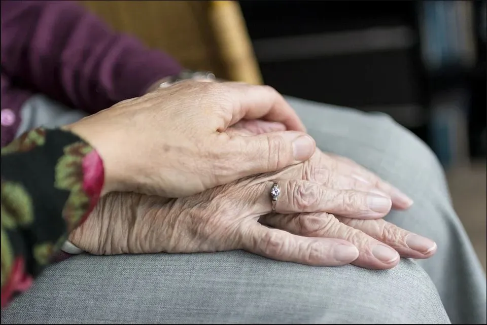 Gros plan sur les caresses de mains de deux personnes âgées
