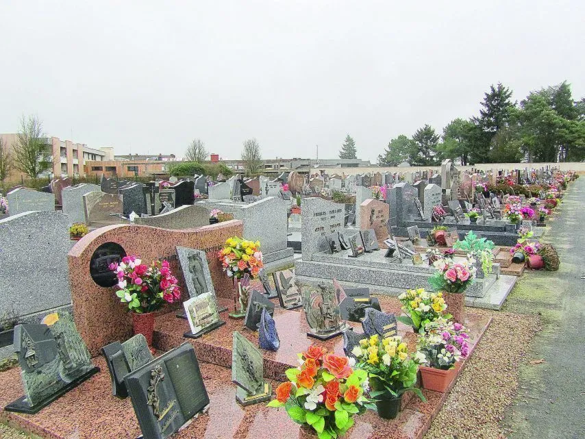 Allée d'un cimetière avec des pierres tombales fleuries